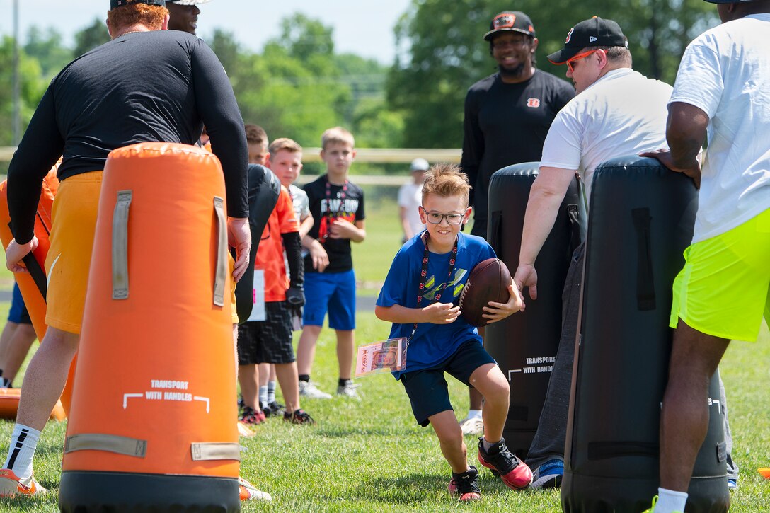 A young boy runs with a football.