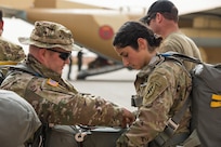 Two U.S. Army Soldiers assigned to the 19th Special Forces Group (Airborne), Utah Army National Guard, help each other attach a reserve parachute while on the tarmac of an airfield in Grier Labouihi, Morocco, waiting to board a Moroccan C-130 during an airborne operation as part of African Lion 22, June 19, 2022.