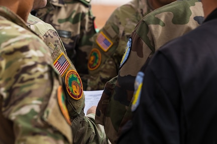 U.S. Army Soldiers assigned to the 19th Special Forces Group (Airborne), Utah Army National Guard, Royal Moroccan Army soldiers, and Tunisian Land Army paratroopers discuss final details on the morning of the friendship airborne operation in Grier Labouihi, Morocco, during African Lion 22, June 19, 2022.