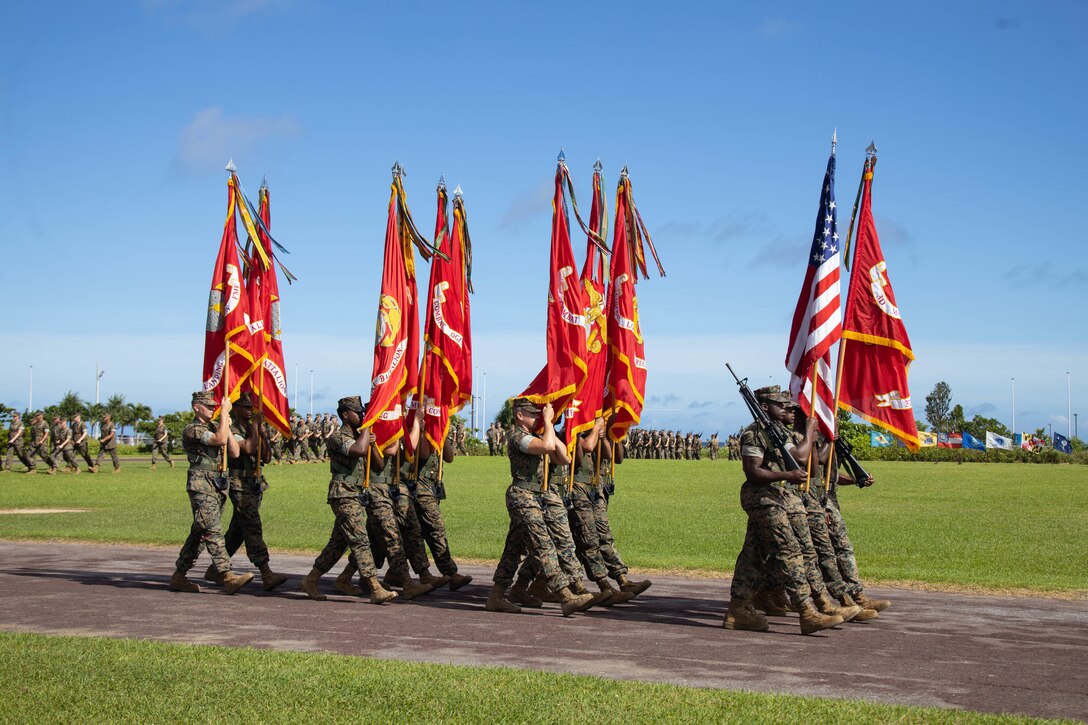 Marines carrying flags march in formation.
