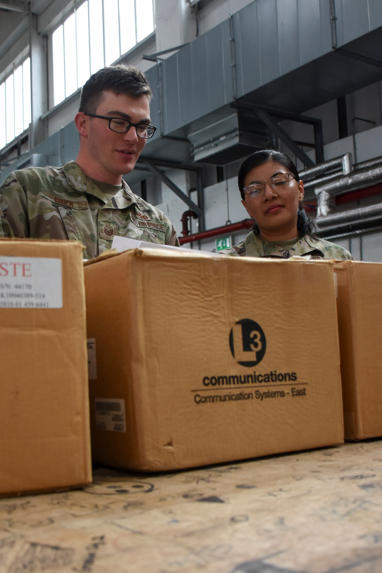 A man and a woman inspect packages on a shipping counter in a warehouse.