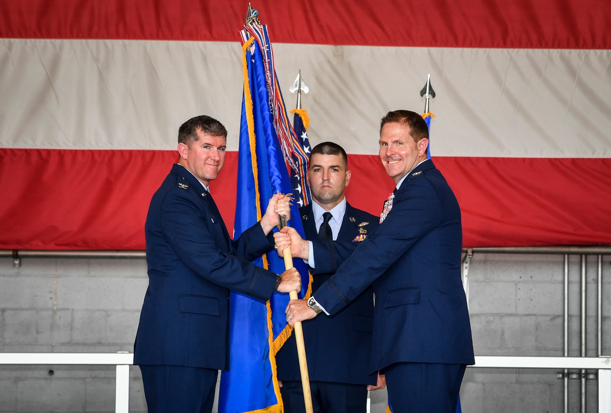 One Air Force members passes a guidon flag to another member.