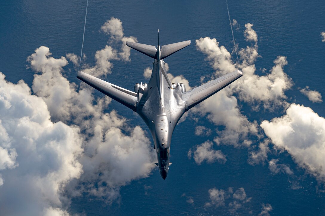 An Air Force aircraft flies over a body of water.