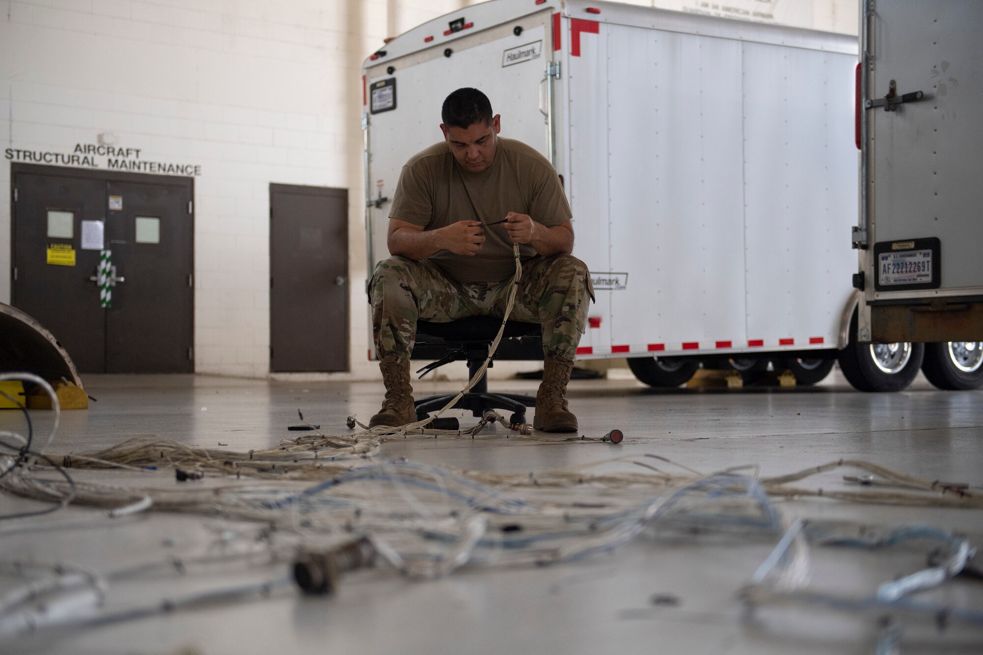 U.S. Air Force Tech. Sgt. Abelino Ledesma, 309th Aircraft Maintenance Group electrical and environmental craftsman, reconfigures electrical wires from an A-10C Thunderbolt II at Moody Air Force Base, Georgia, June 21, 2022. The 309th AMXG arrived from Hill Air Force Base, Utah, to remove and replace the wings on an A-10C. The wires from the old wing were taken out, recycled and configured together to fit into the new wing. (U.S. Air Force photo by Airman 1st Class Rachel Coates)