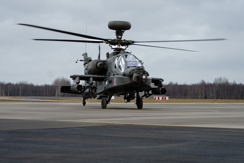 A military helicopter is in an airfield.