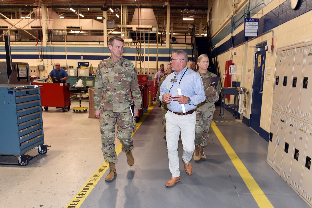Photo shows group of people walking down a thoroughfare in a hangar