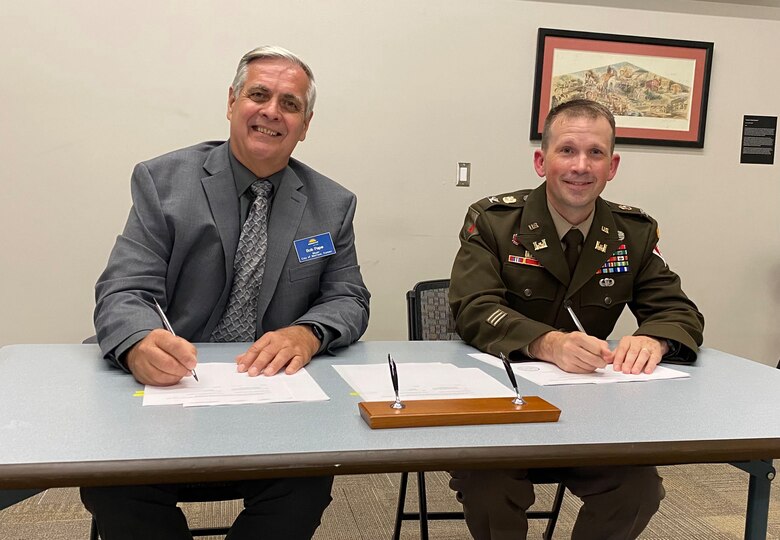 Bob Pape, City of Merriam mayer (left), and Col. Travis Rayfield, U.S. Army Corps of Engineers, Kansas City District commander (right), seated at a table to sign the design agreement.