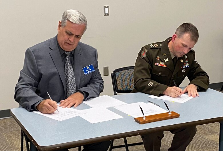 Bob Pape, City of Merriam mayer (left), and Col. Travis Rayfield, U.S. Army Corps of Engineers, Kansas City District commander (right), seated at a table to sign the design agreement.
