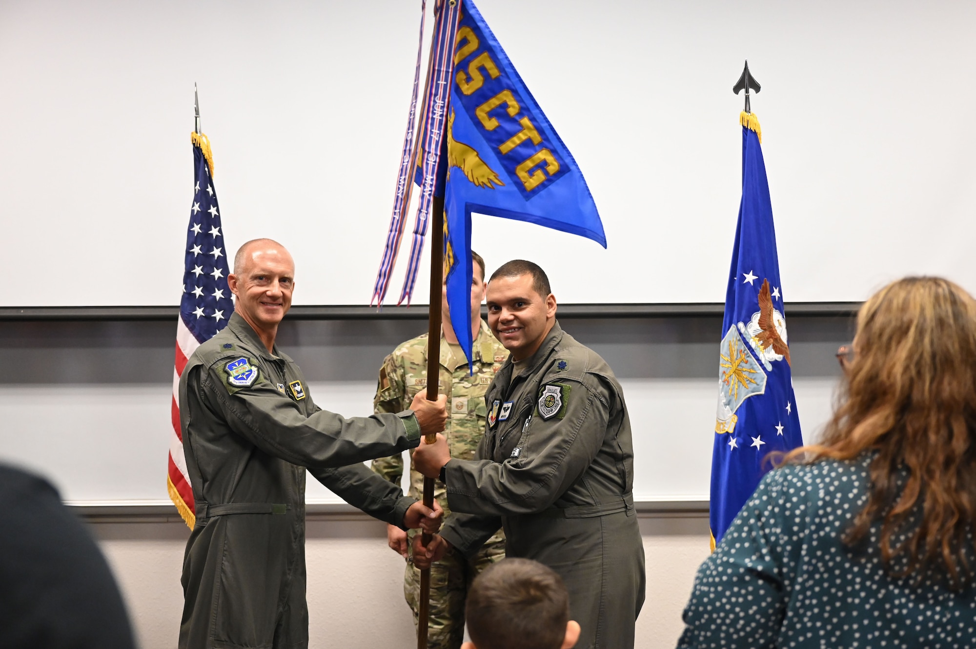 photo of two USAF Airmen holding unit guidon flag between them with USAF Airmen standing behind them