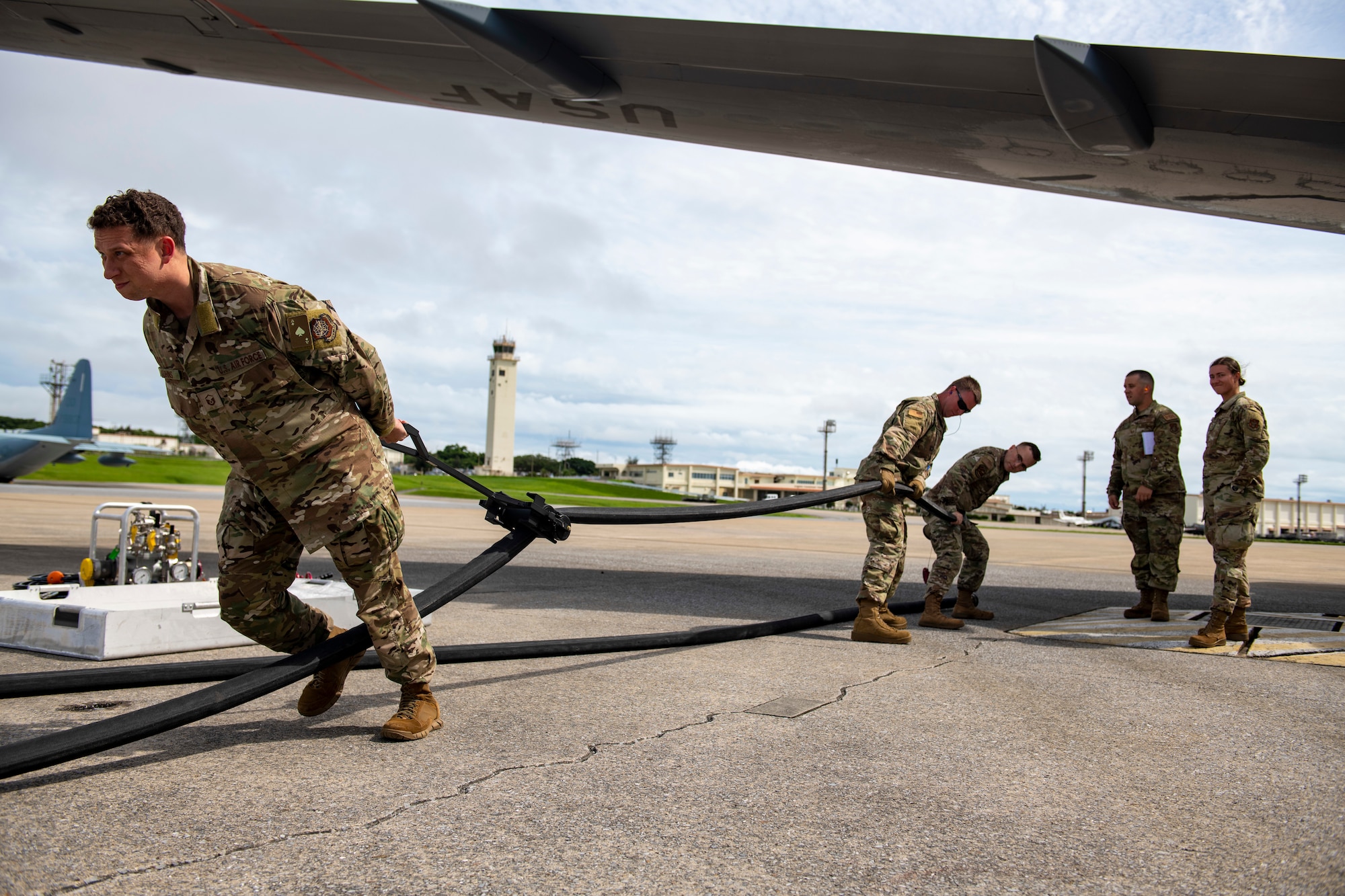 Airmen from the 18th LRS remove excess fuel from a hose after refueling a KC-46.
