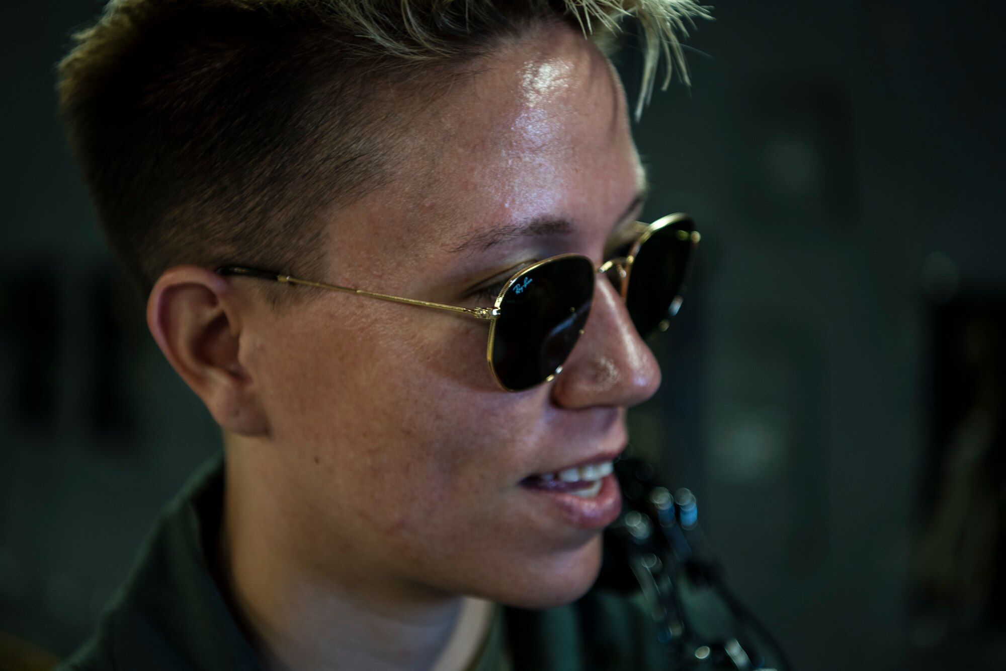 A woman in a flight suit watches a large door open on a large military airplane.