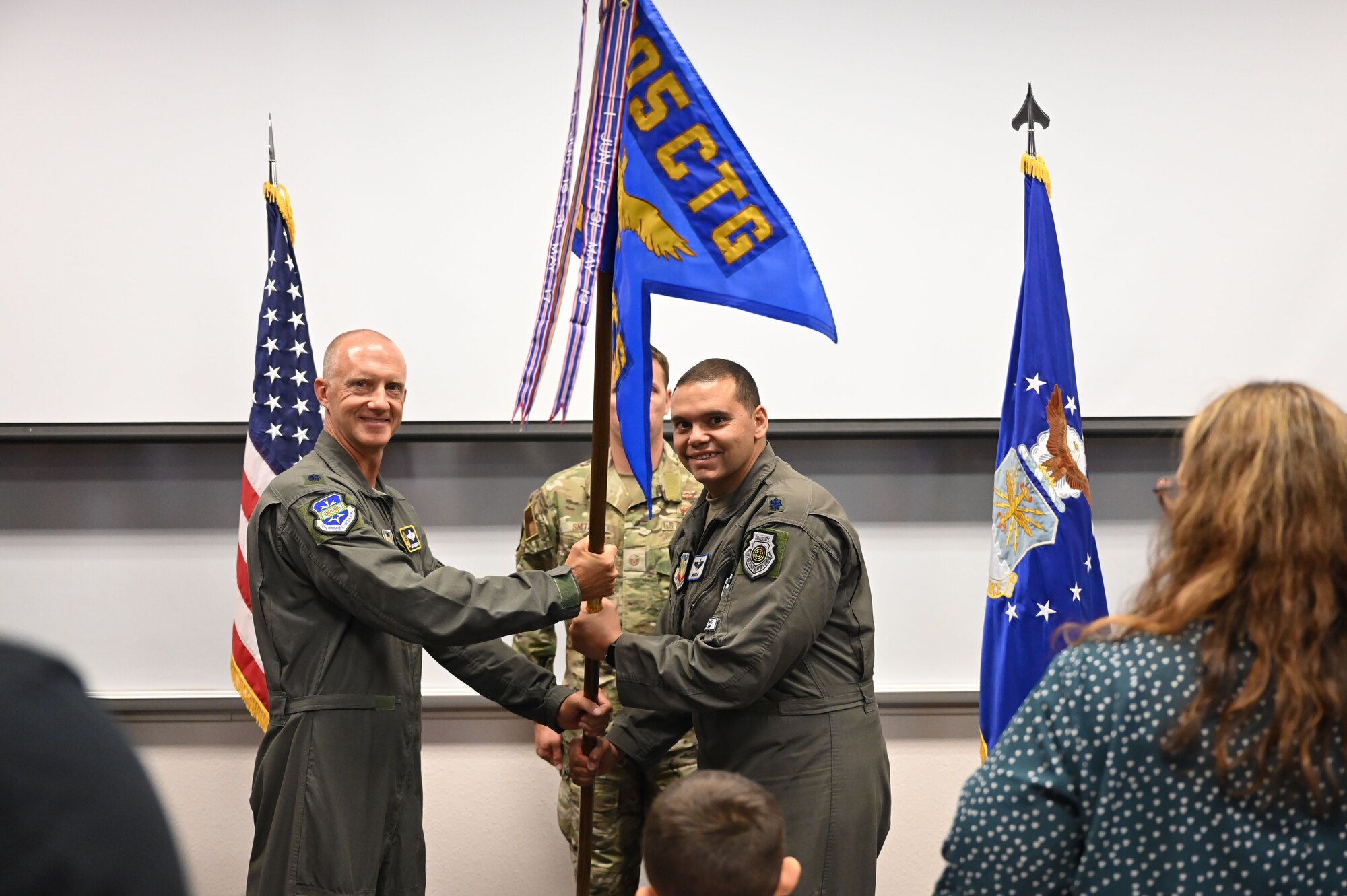 photo of two USAF Airmen holding unit guidon flag between them with USAF Airmen standing behind them