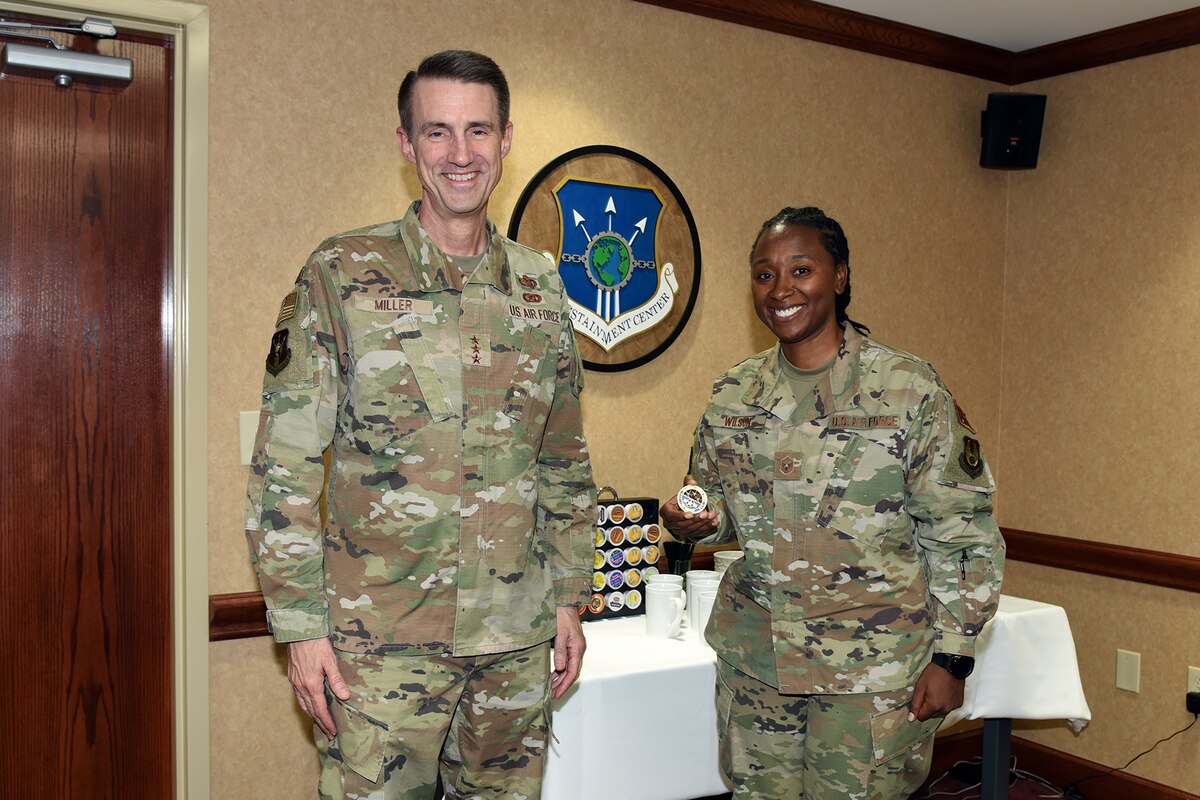 Photo shows two people standing while one holds a coin