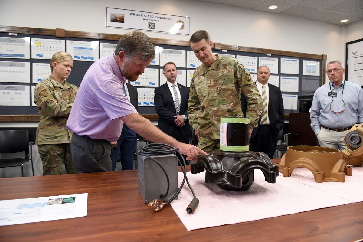 Photo shows people looking at piece of equipment on a table