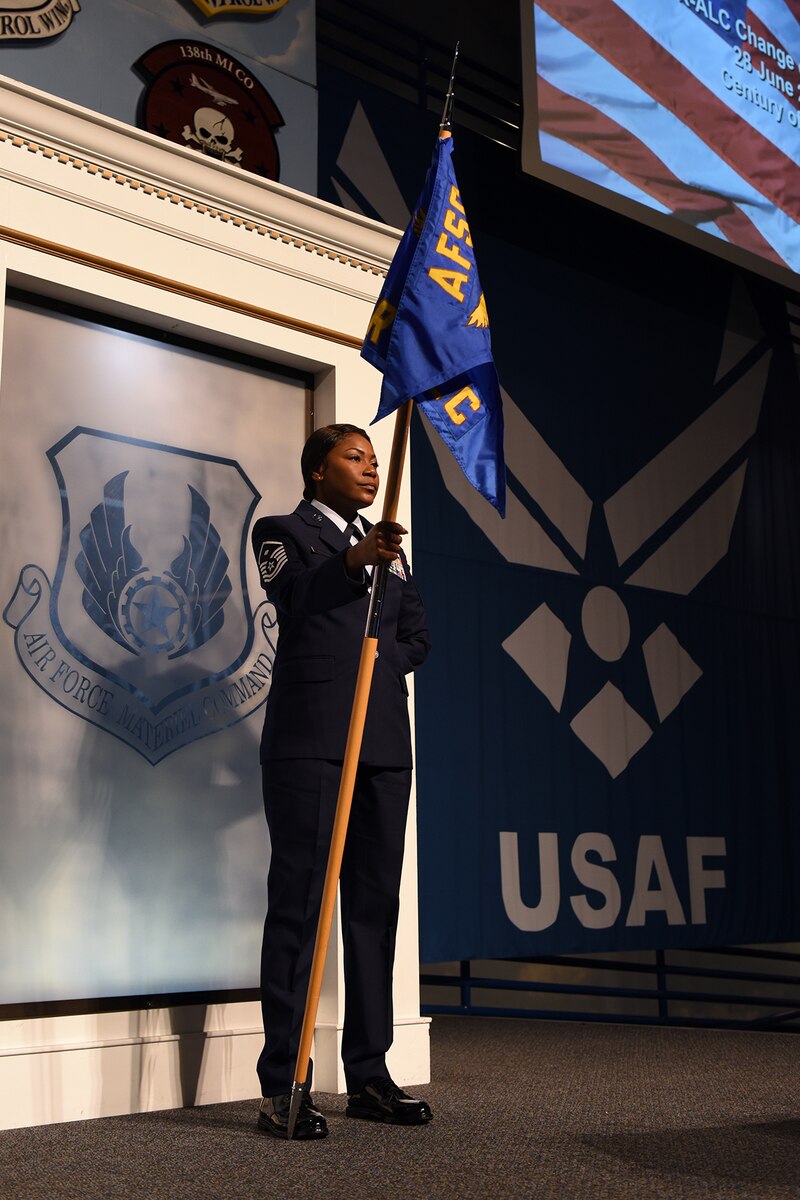 Photo shows an Airmen standing by herself holding a guidon.