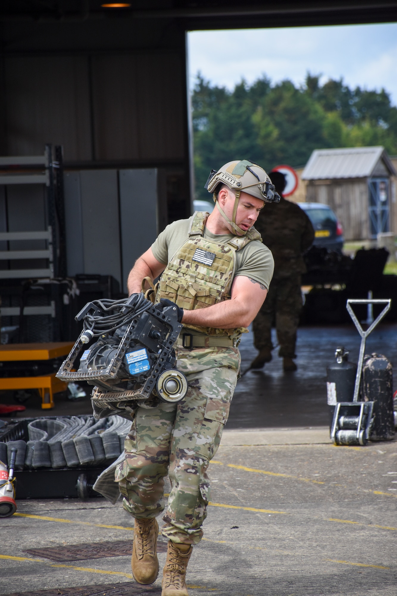 A man walks with a portable fuel pump used for forward area refueling point operations.