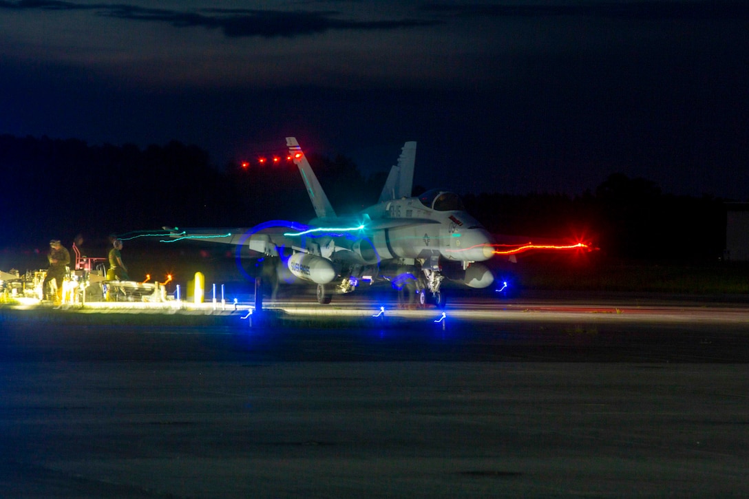 An aircraft taxis a runway at night.