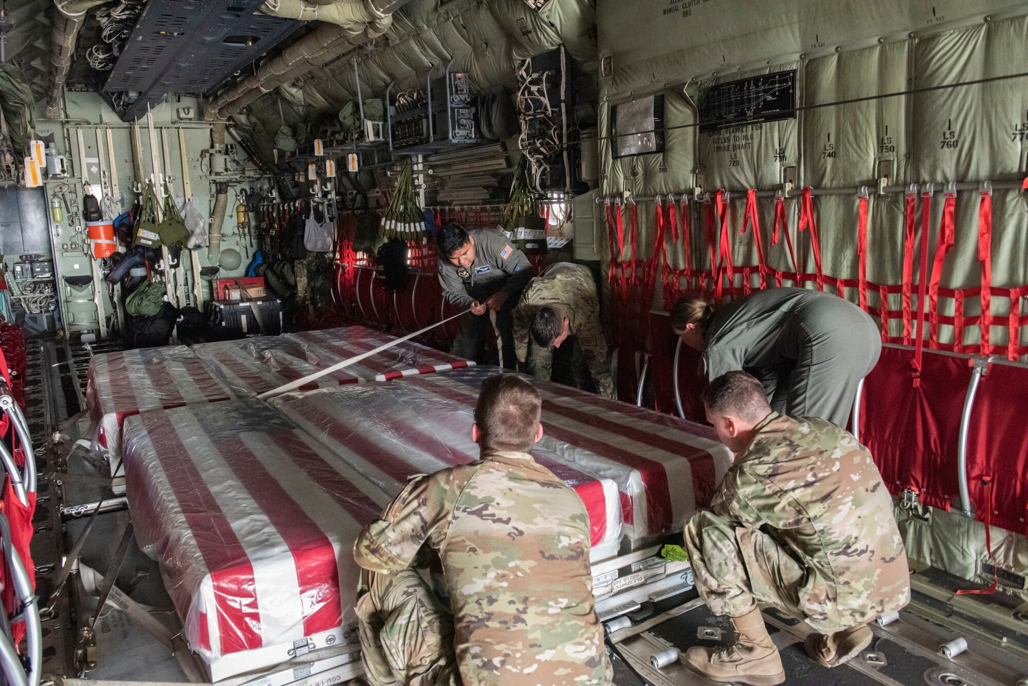 U.S. Air Force Airmen secure nine caskets containing remains of unidentified service members in a C-130 Hercules at Aviano Air Base, June 27, 2022