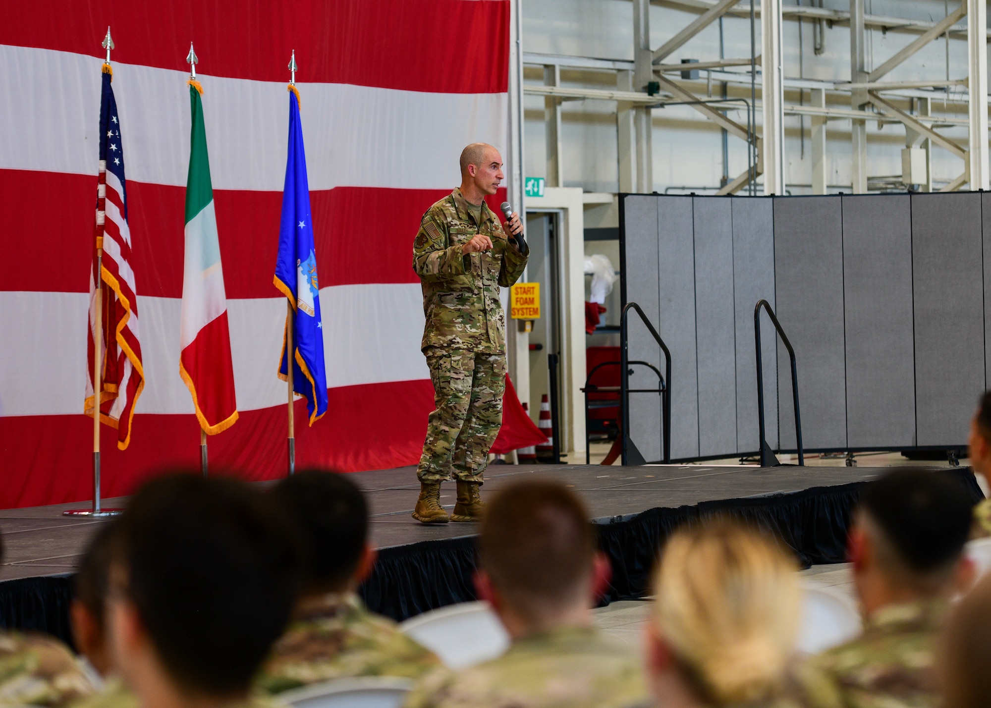 U.S. Air Force Brig. Gen. Jason Bailey, 31st Fighter Wing commander, gives his final all-call to the 31st FW at Aviano Air Base, Italy, June 30, 2022. During the all-call, Bailey had a question and answer session. With approximately 4,200 active-duty military members, nearly 300 U.S. civilians and 700 Italian civilian employees, the wing conducts and supports air combat operations, and maintains munitions for NATO. (U.S. Air Force photo by Senior Airman Brooke Moeder)