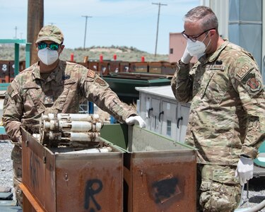 U.S. Air Force National Guard Master Sgt. Timothy R. Edwards, Explosive Ordnance Disposal flight chief, (left) and Master Sgt. Derin Creek, EOD Techinician, (right) inspects a contaminated container of depleted uranium on June 23, 2022 at Tooele Army Depot, UT.