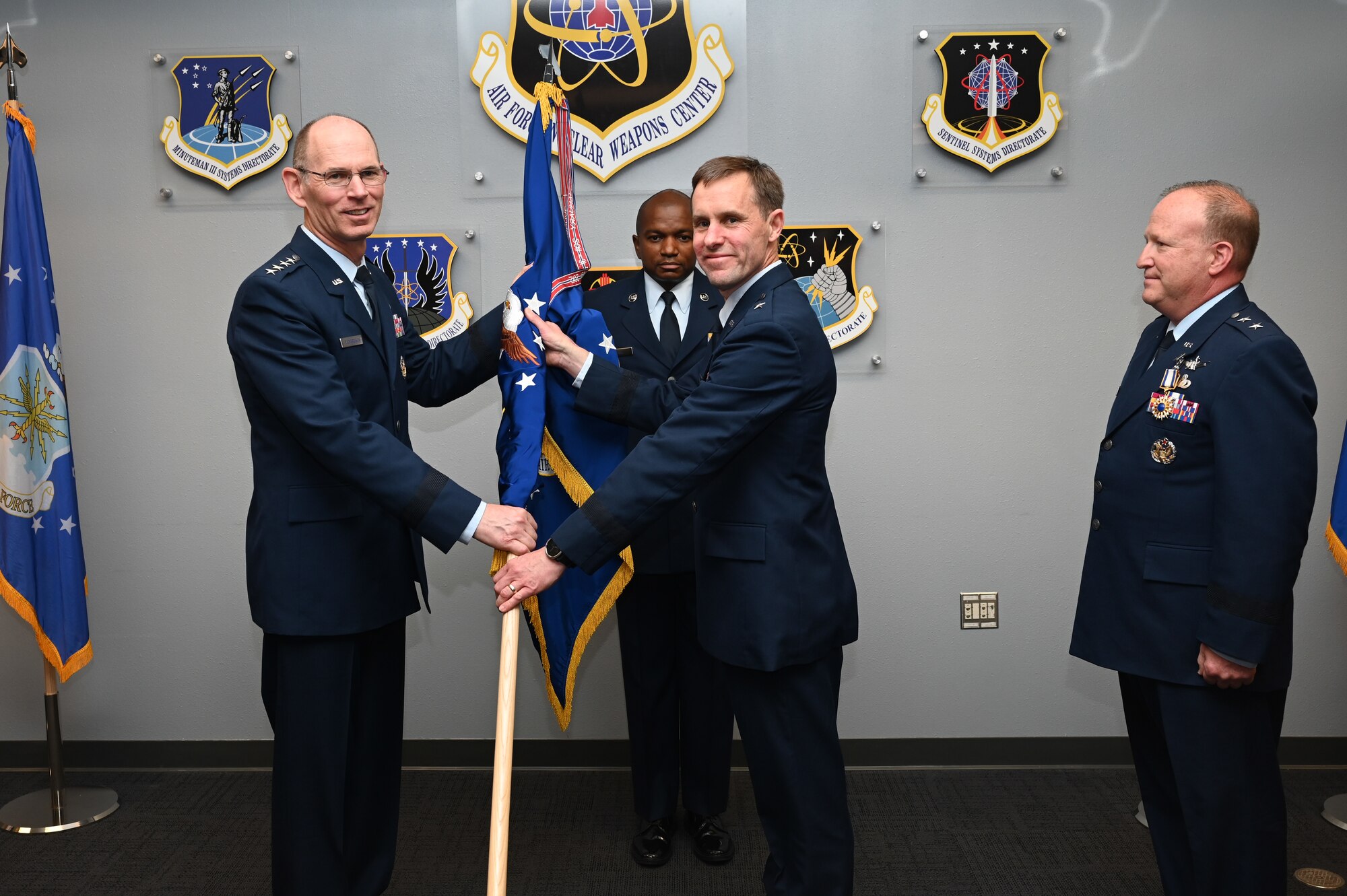 Gen. Duke Z. Richardson (left), commander of Air Force Materiel Command, hands the Air Force Nuclear Weapons Center flag to Brig. Gen. John P. Newberry, incoming AFNWC commander, during the change of command from Maj. Gen. Anthony W. Genatempo (right), outgoing commander, at Kirtland Air Force Base, New Mexico, June 21, 2022. Newberry previously served as program executive officer for bombers and director of the Air Force Life Cycle Management Center’s Bombers Directorate at Wright-Patterson Air Force Base, Ohio. (U.S. Air Force photo by Staff Sgt. Miranda Loera)