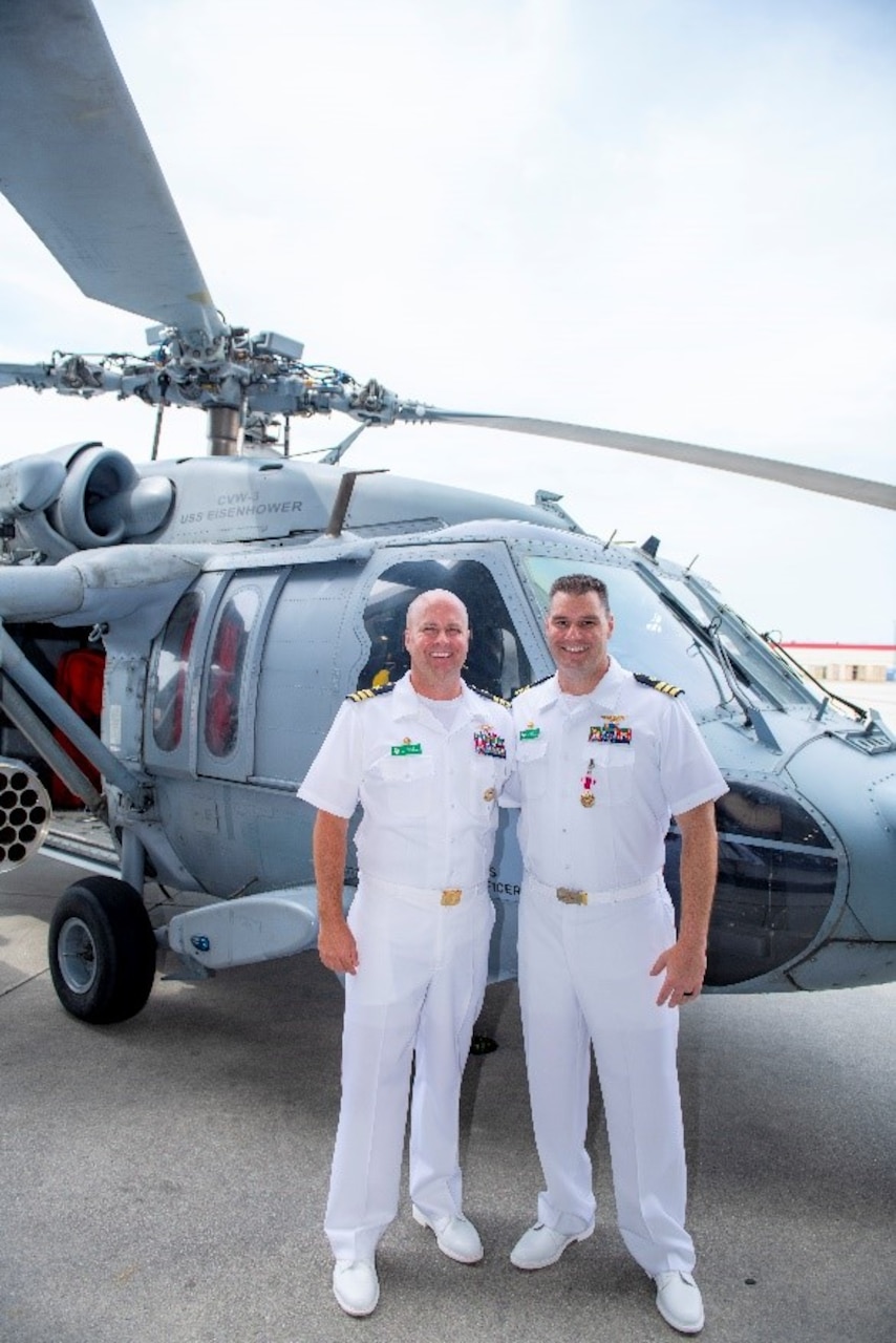 Naval Officers stand in front of a helicopter