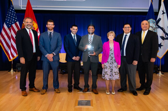 Mr. Tommy Ross, Performing the Duties of ASN RDA, left, and Mr. Frederick J. (Jay) Stefany, Principal Civilian Deputy to ASN RDA, right, present a team award to members of the Cyber Red Team at Naval Undersea Warfare Center (NUWC) Newport Division during the June 16 ceremony for the Assistant Secretary of the Navy (ASN) for Research, Development and Acquisition (RDA) Dr. Delores M. Etter Top Scientists and Engineers for 2022.