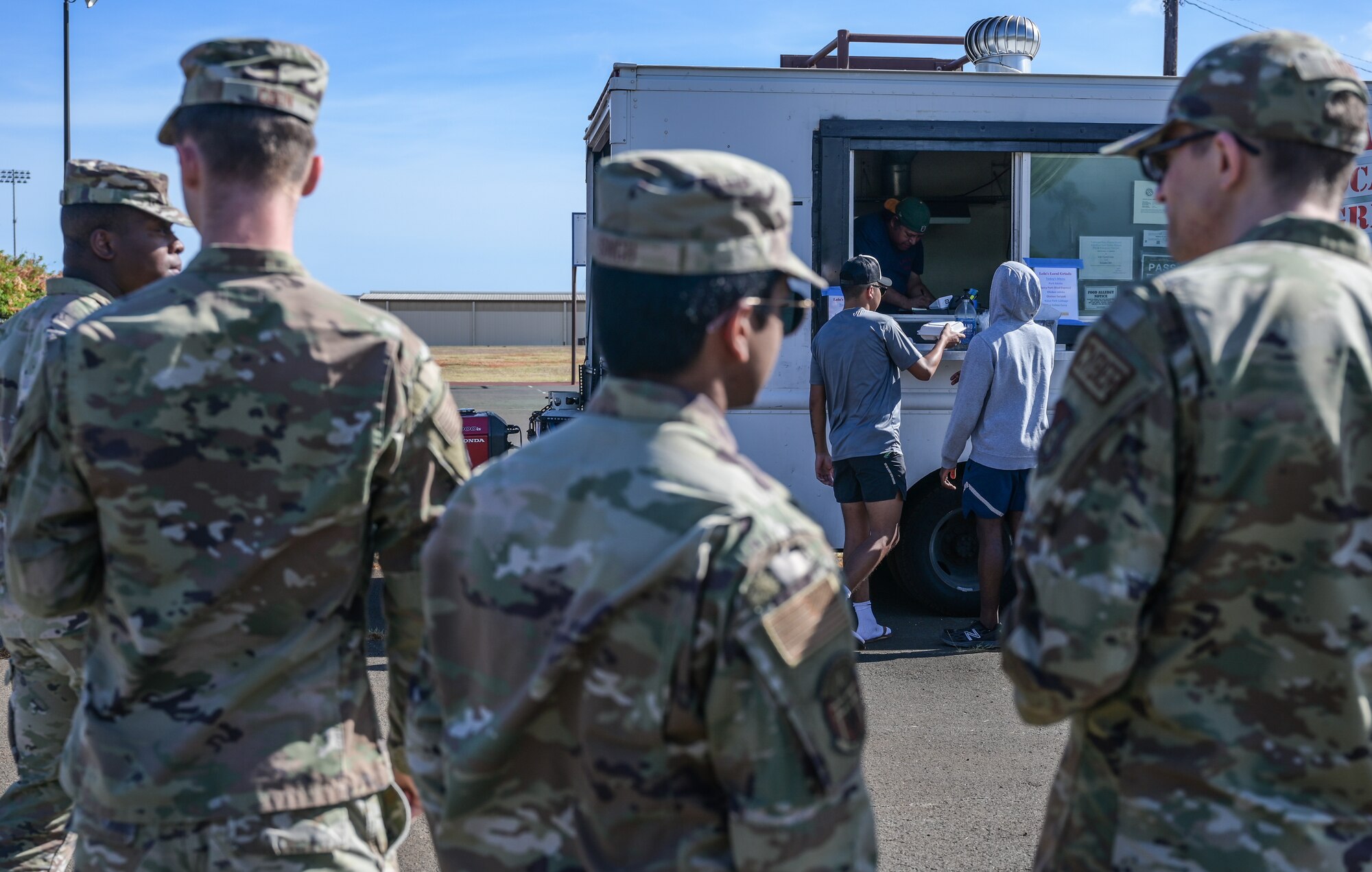 Military dorm residents enjoy free food during a “Feed the Dorms” event near the Hale Aina Dining Facility at Joint Base Pearl Harbor-Hickam, Hawaii, June 29, 2022. The event was hosted by the Hickam Chief’s Group, providing residents with 100 free meals. (U.S. Air Force photo by Staff Sgt. Alan Ricker)