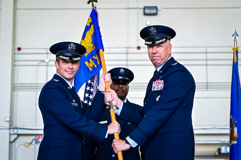 U.S. Air Force Col. Scott Wiederholt, 305th Air Mobility Wing commander, passes the flag to U.S. Air Force Col. Scott Pendely, 305th Maintenance Group commander, as he takes commands at Joint Base McGuire-Dix-Lakehurst, N.J., June 30, 2022. U.S. Air Force Col. Mary Teeter relinquished command to Pendley after having led CAN DO Airmen during the COVID-19 pandemic and Operations Allies Welcome/Refuge.