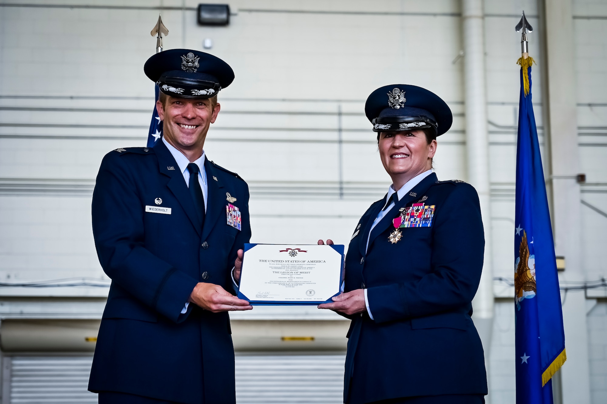 U.S. Air Force Col. Scott Wiederholt, 305th Air Mobility Wing commander, presents the Legion of Merit award to U.S. Air Force Col. Mary Teeter, 305th Maintenance Group commander,  at Joint Base McGuire-Dix-Lakehurst, N.J., June 30, 2022. Teeter relinquished command to U.S. Air Force Col. Scott Pendley after having led CAN DO Airmen during the COVID-19 pandemic and Operations Allies Welcome/Refuge.