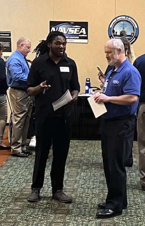 IMAGE: Naval Surface Warfare Center Dahlgren Division (NSWCDD) recruiters converse with a job candidate at the NSWCDD-sponsored Career Fair June 27 at the Fredericksburg Expo and Conference Center.