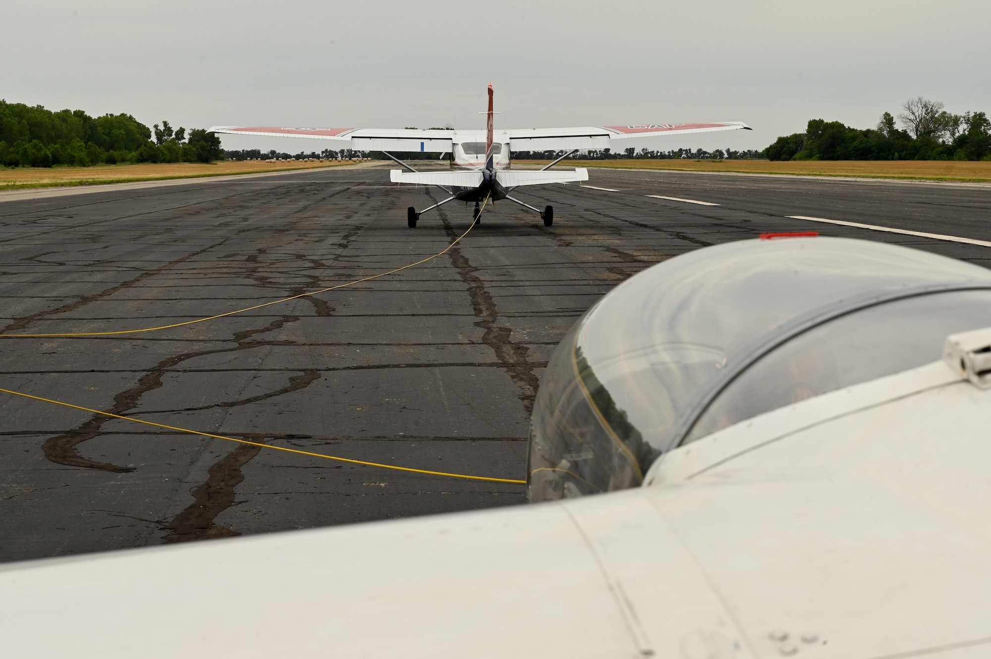 A Cessna 182 Skylane prepares to pull an L-23 Super Blanik glider into the air June 27, 2022, at the Sunflower Gliderport in Hutchinson, Kansas. The Cessna pulls the glider into the air with a guide rope and releases it once the glider has reached a high enough speed for it to maintain enough lift to stay in the air. (U.S. Air Force photo by Senior Airman Zachary Willis)