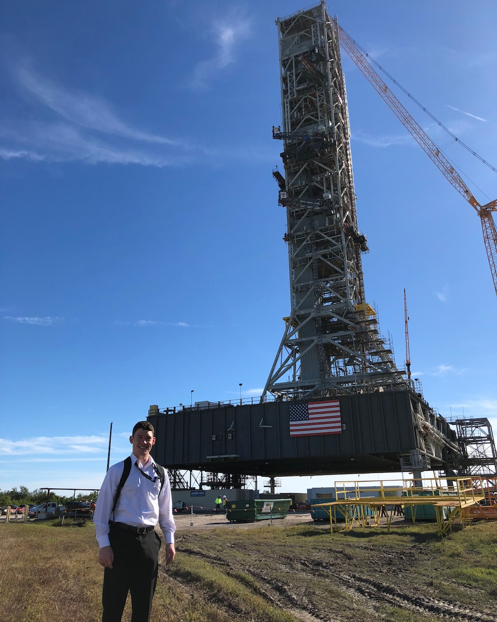 A man stands in front of a large spacecraft outside.