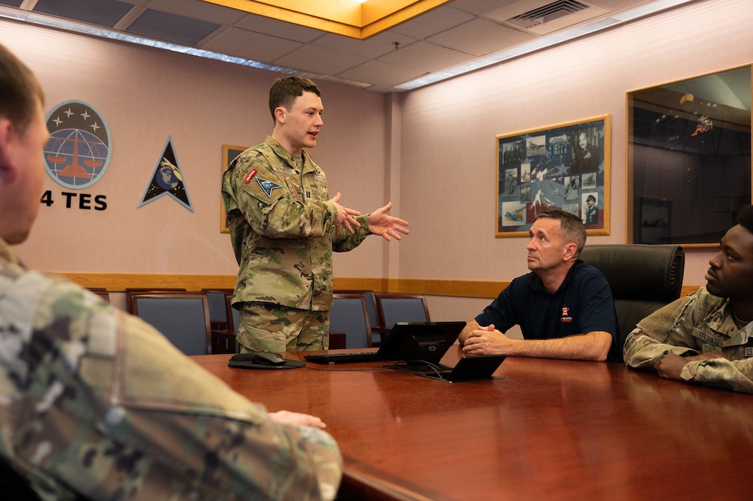 A standing guardian talks to personnel seated at a table.