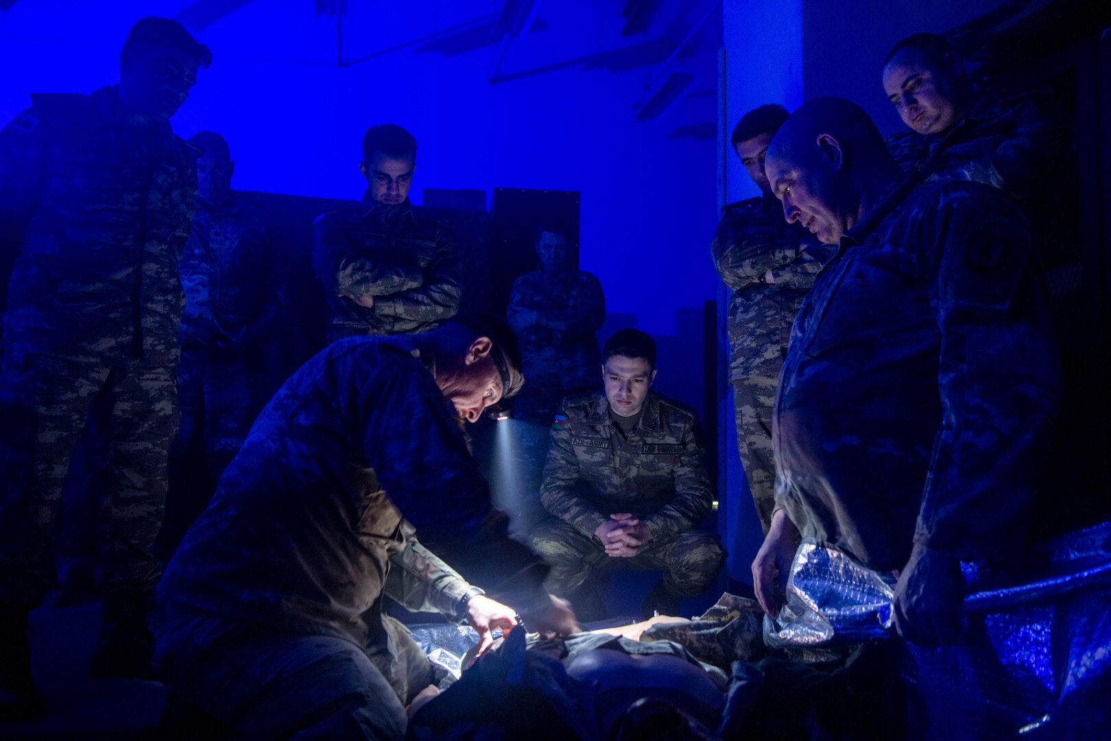 people in dark room treating simulated wounded patient