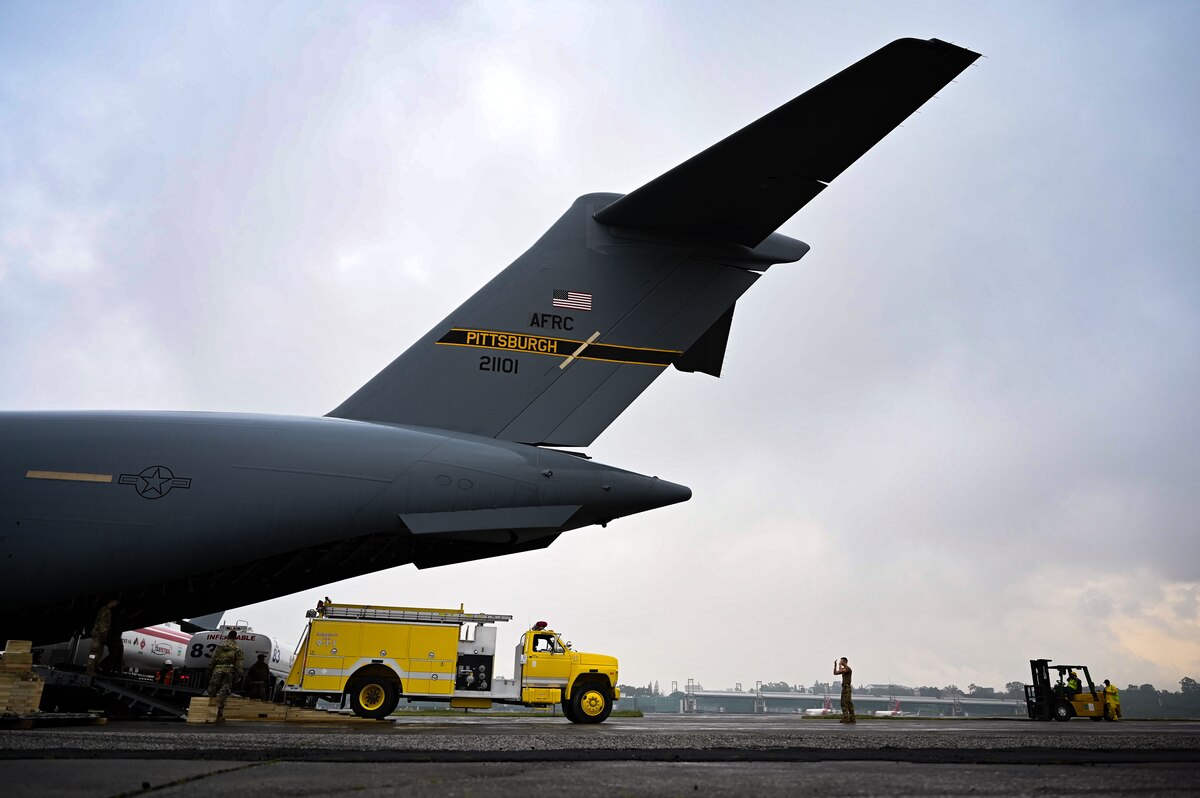 Photo shows people directing a firetruck out of the back of a C-17 Globemaster III.