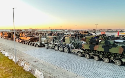 A line of military Heavy Equipment Transport line-haul trucks is staged at Coleman work site in Mannheim, Germany. Each truck is hauling equipment and vehicles, such as M1 Abrams main battle tanks as seen here, to Grafenwoehr Training Area in Germany. There, the vehicles and equipment pieces will be issued to the 1st Armored Brigade Combat Team, 3rd Infantry Division deploying to Germany from Fort Stewart, Georgia. (U.S. Army Photo by Maj. Allan Laggui)