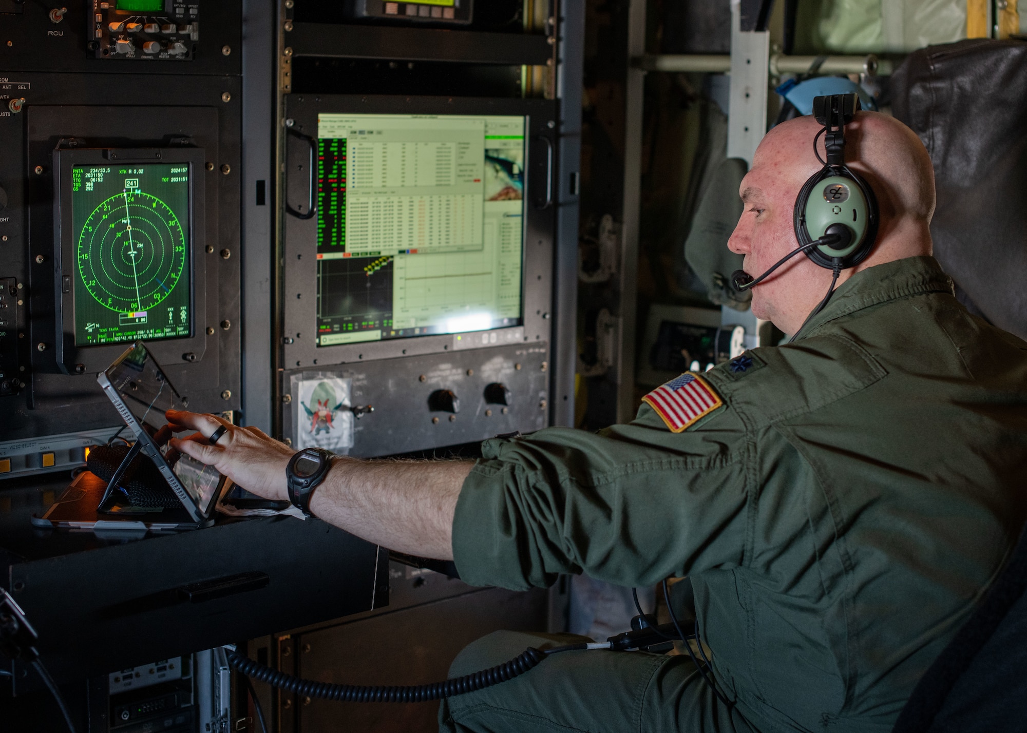 Lt. Col. Baker sits right looking left at screens while working on an iPad.