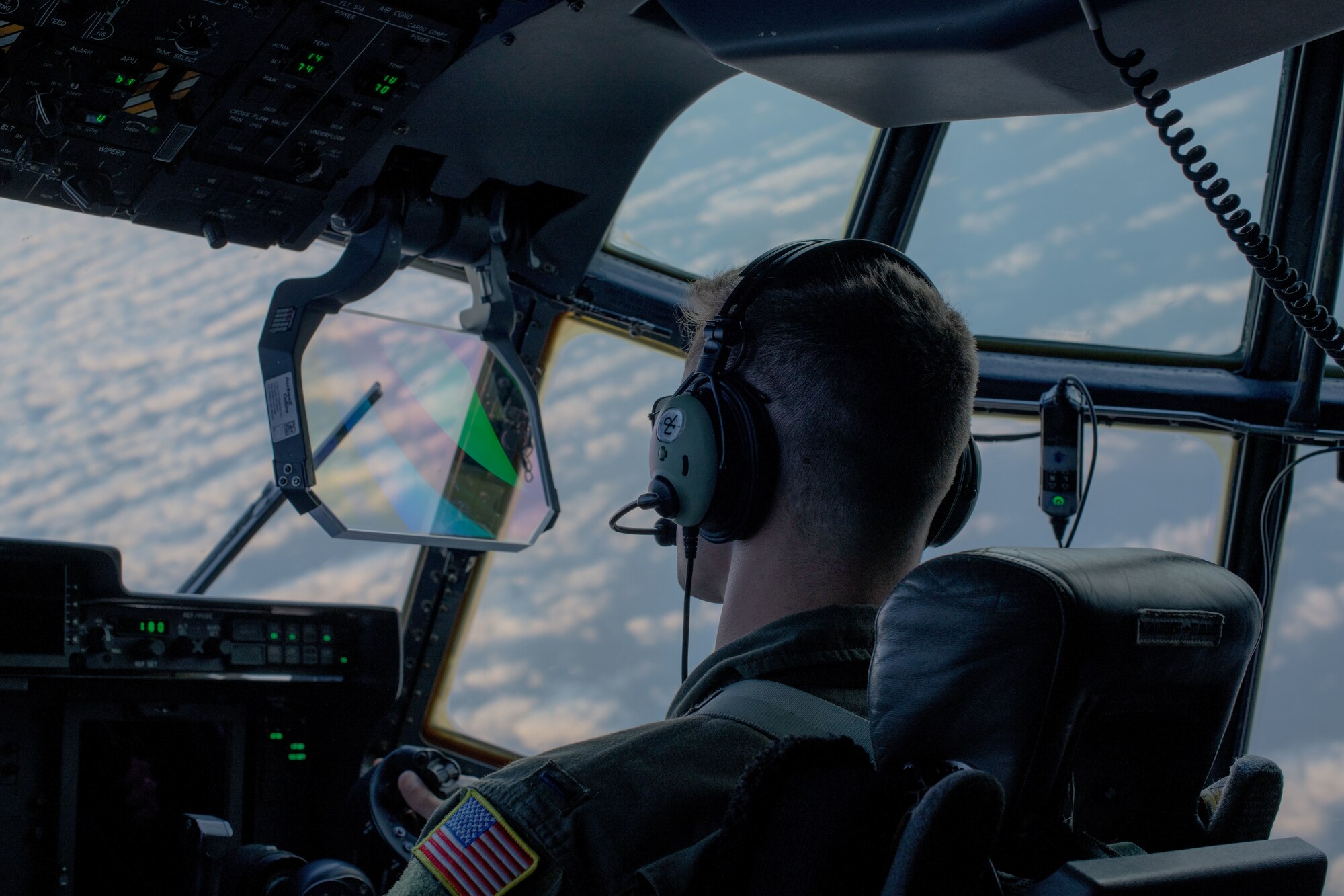 A pilot controls an aircraft banking right. clouds can be seen through the window.