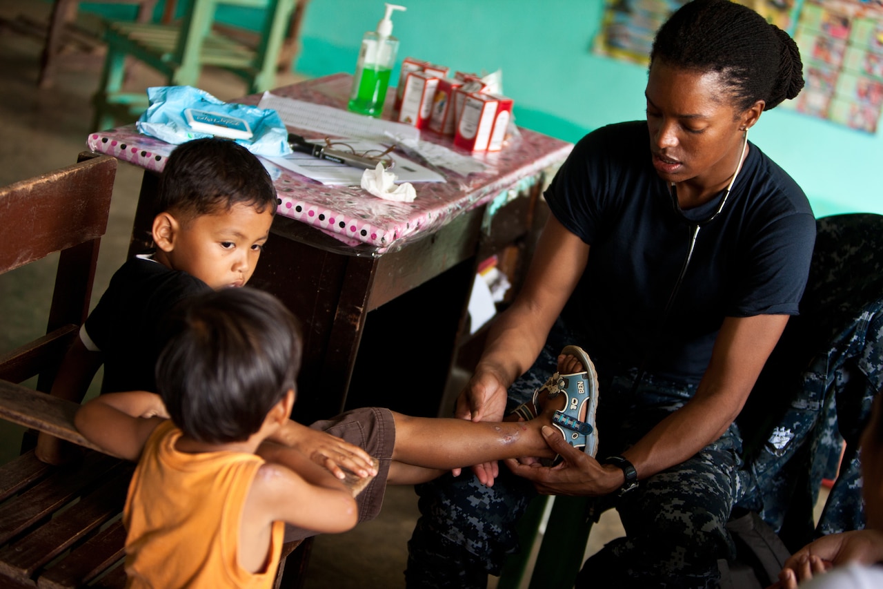 A woman examines the leg of a young boy.