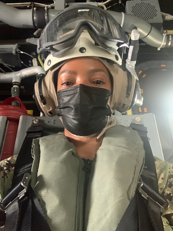 A woman wears helicopter fight gear and a medical mask.
