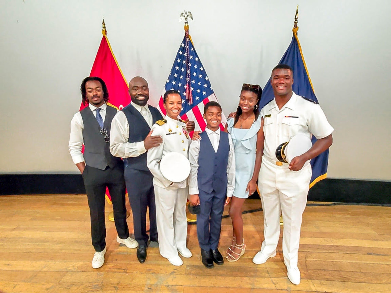 Six members of a family pose in front of flags.
