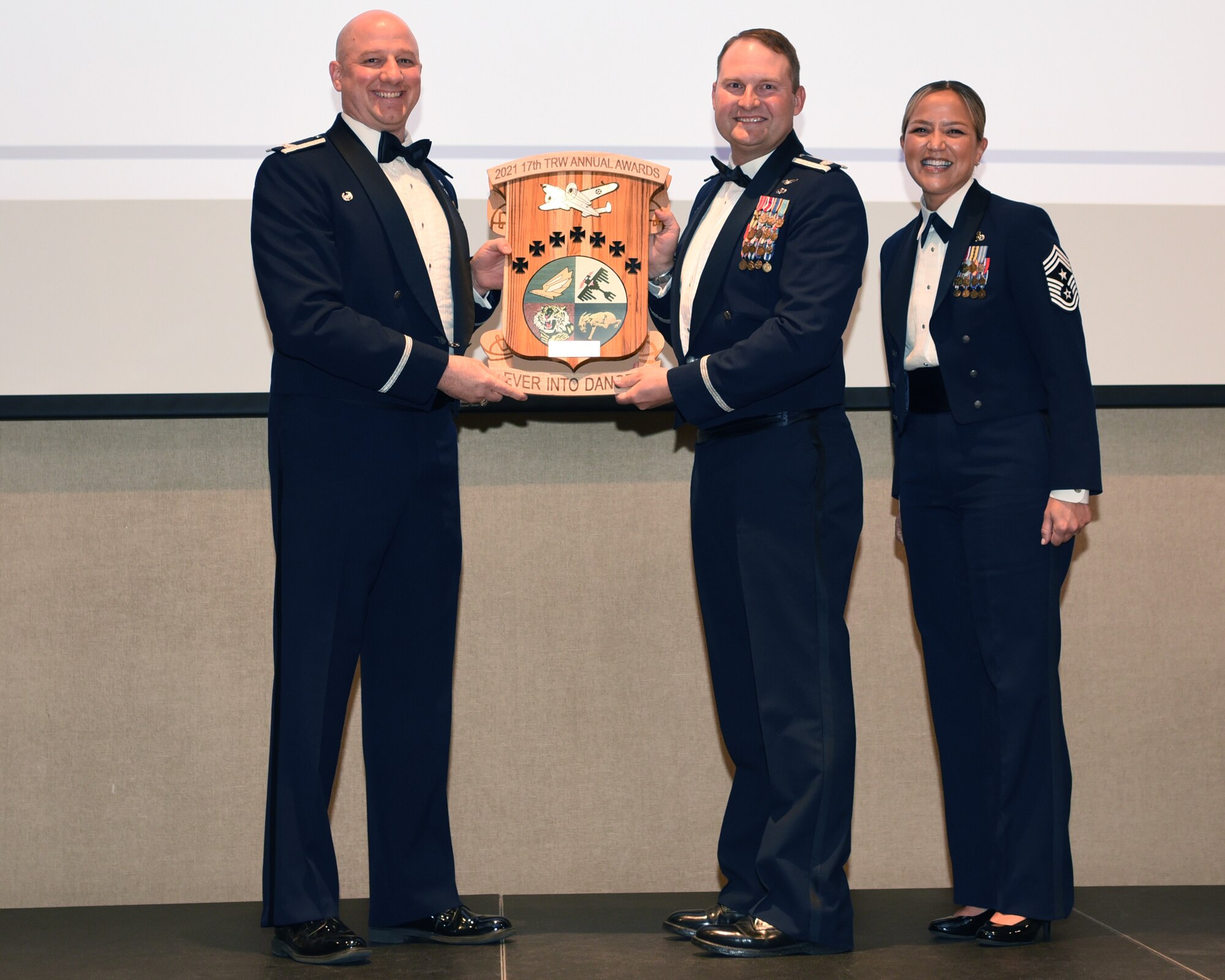 U.S. Air Force Col. Matthew Reilman, 17th Training Wing commander, presents an award to Lt. Col. John Bergmans, 315th Training Squadron commander and proxy to the Key Spouse of the Year award recipient, during the 29th Annual Awards Ceremony at the McNease Convention Center, San Angelo, Texas, Feb. 26, 2022. The 315th TRS also garnered the Unit of the Year award.  (U.S. Air Force photo by Senior Airman Abbey Rieves)