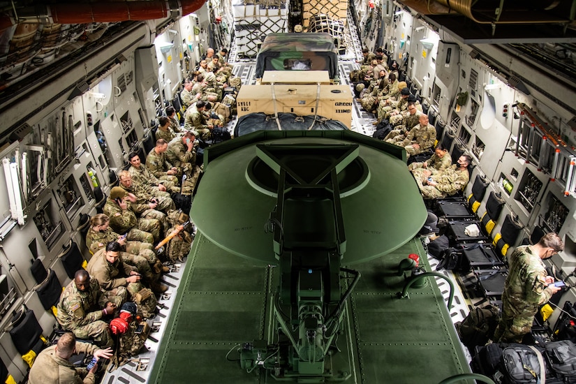 Paratroopers sit in jump seats along the side of a C-17 transport.