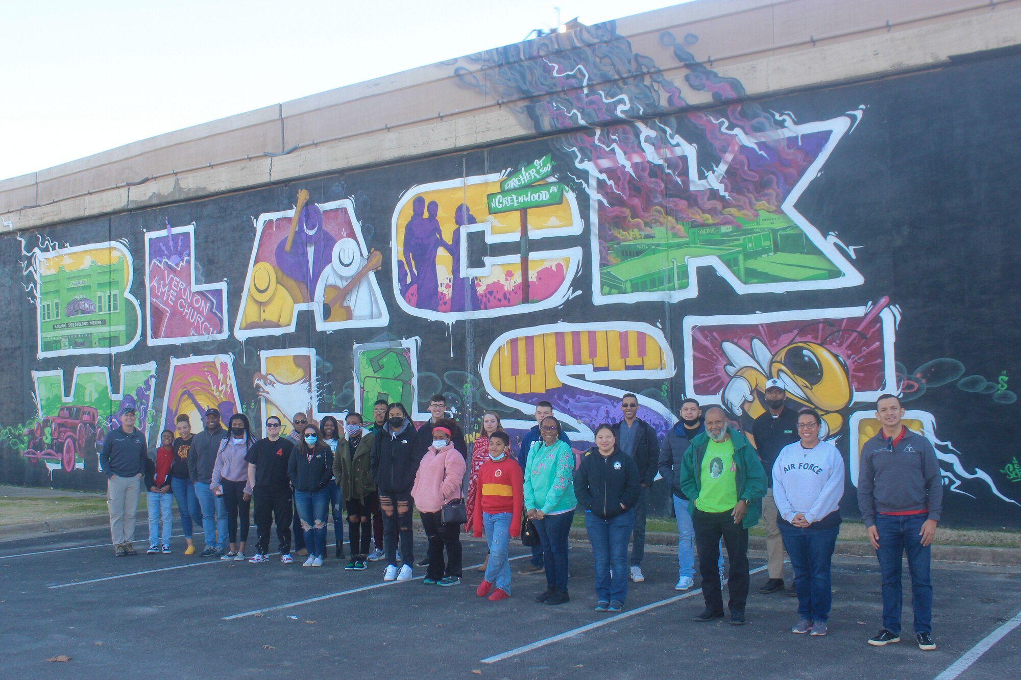 people stand in front of mural