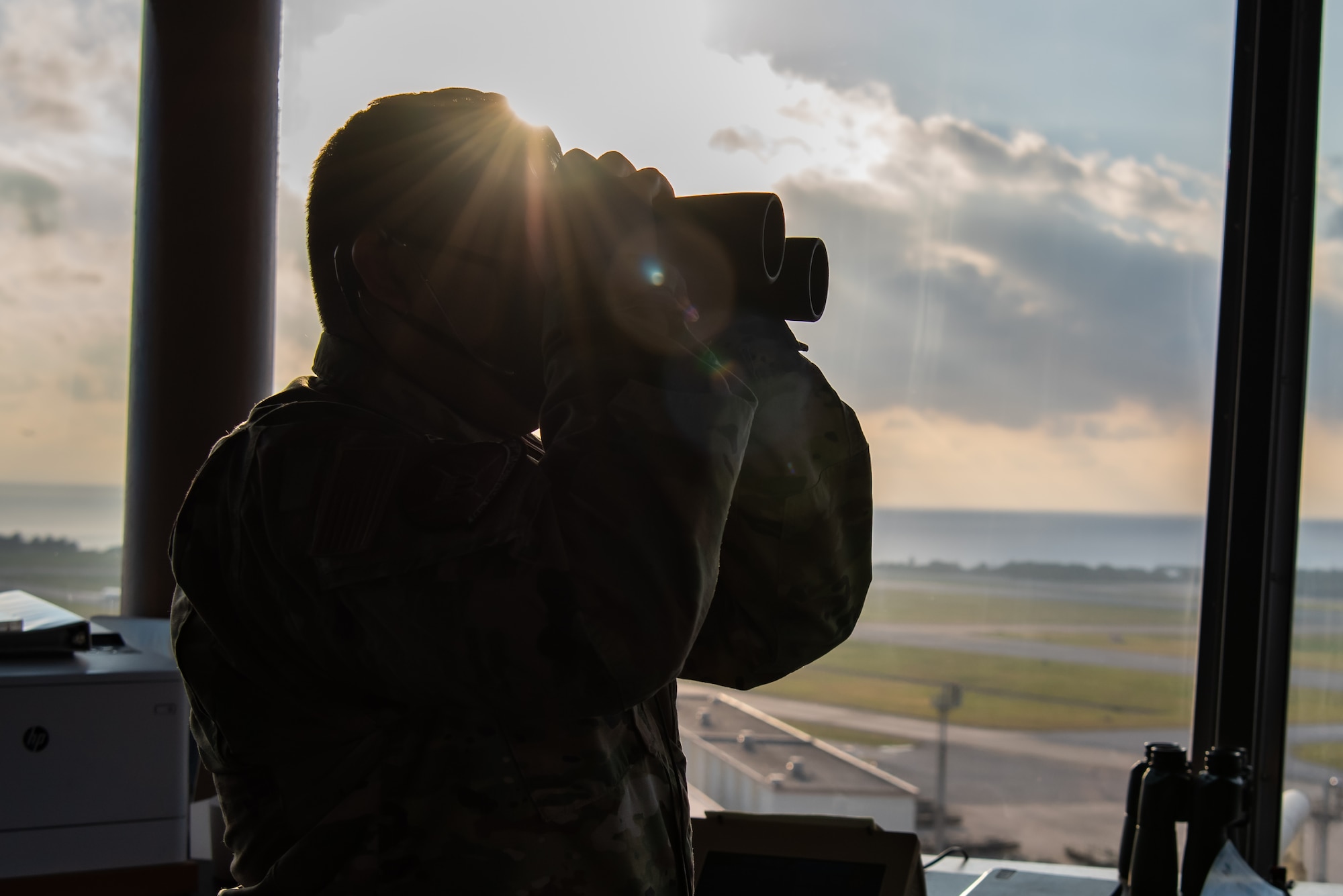 An Airman uses binoculars to scan the flightline.