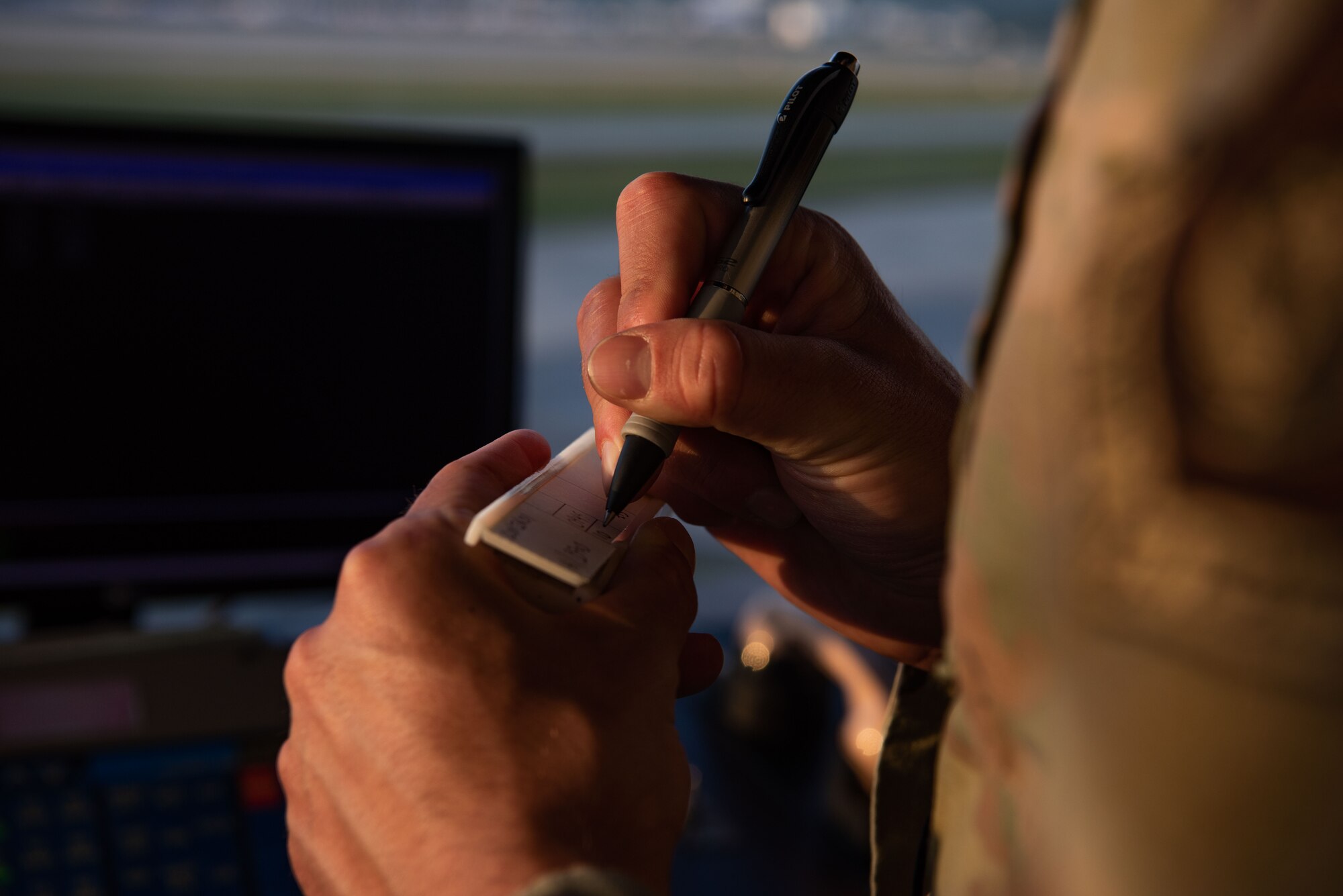 A close up as an Airman writes down information.