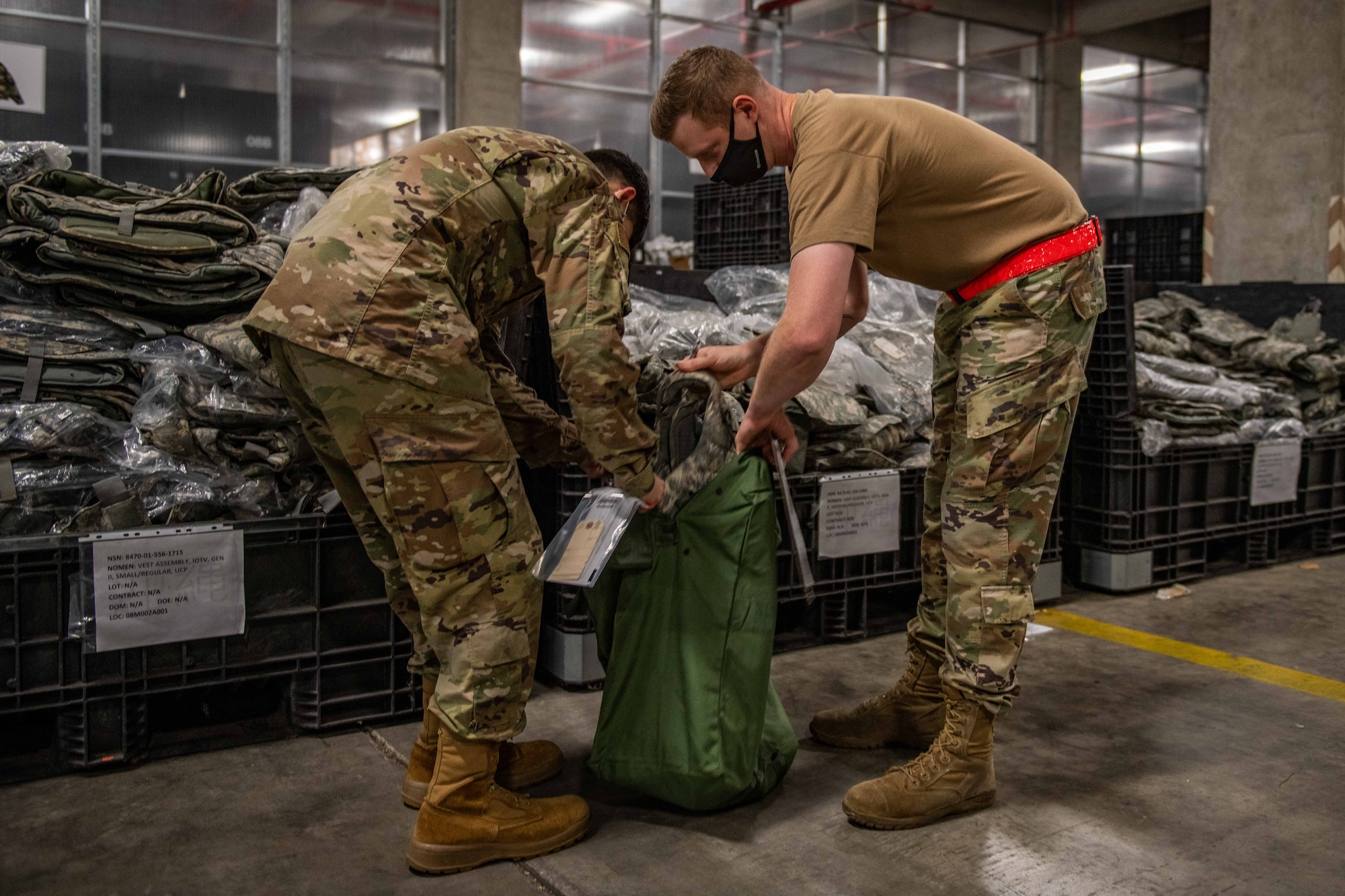 An Airman gets help packing his gear bag