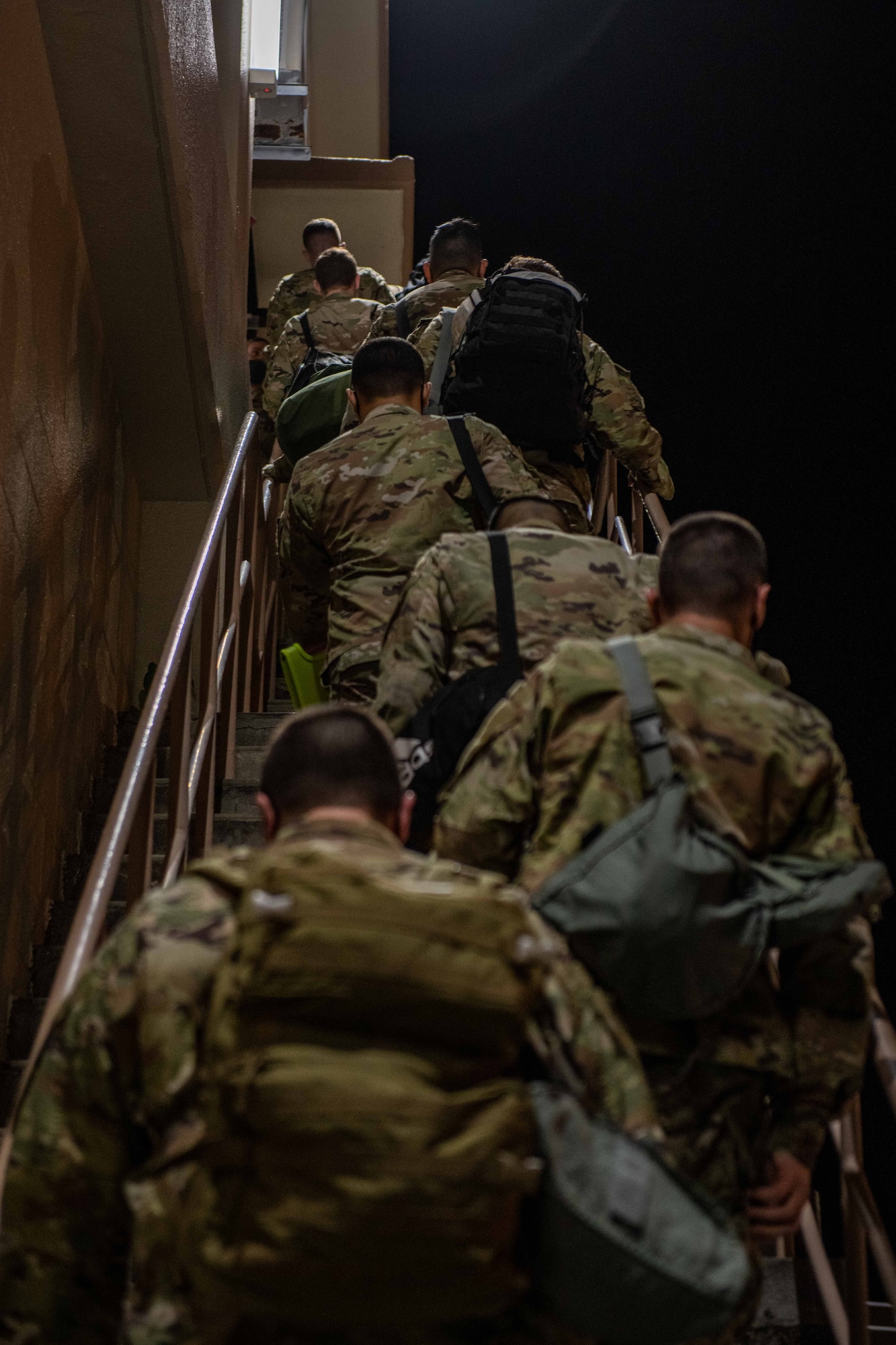A line of Airmen walk up stairs