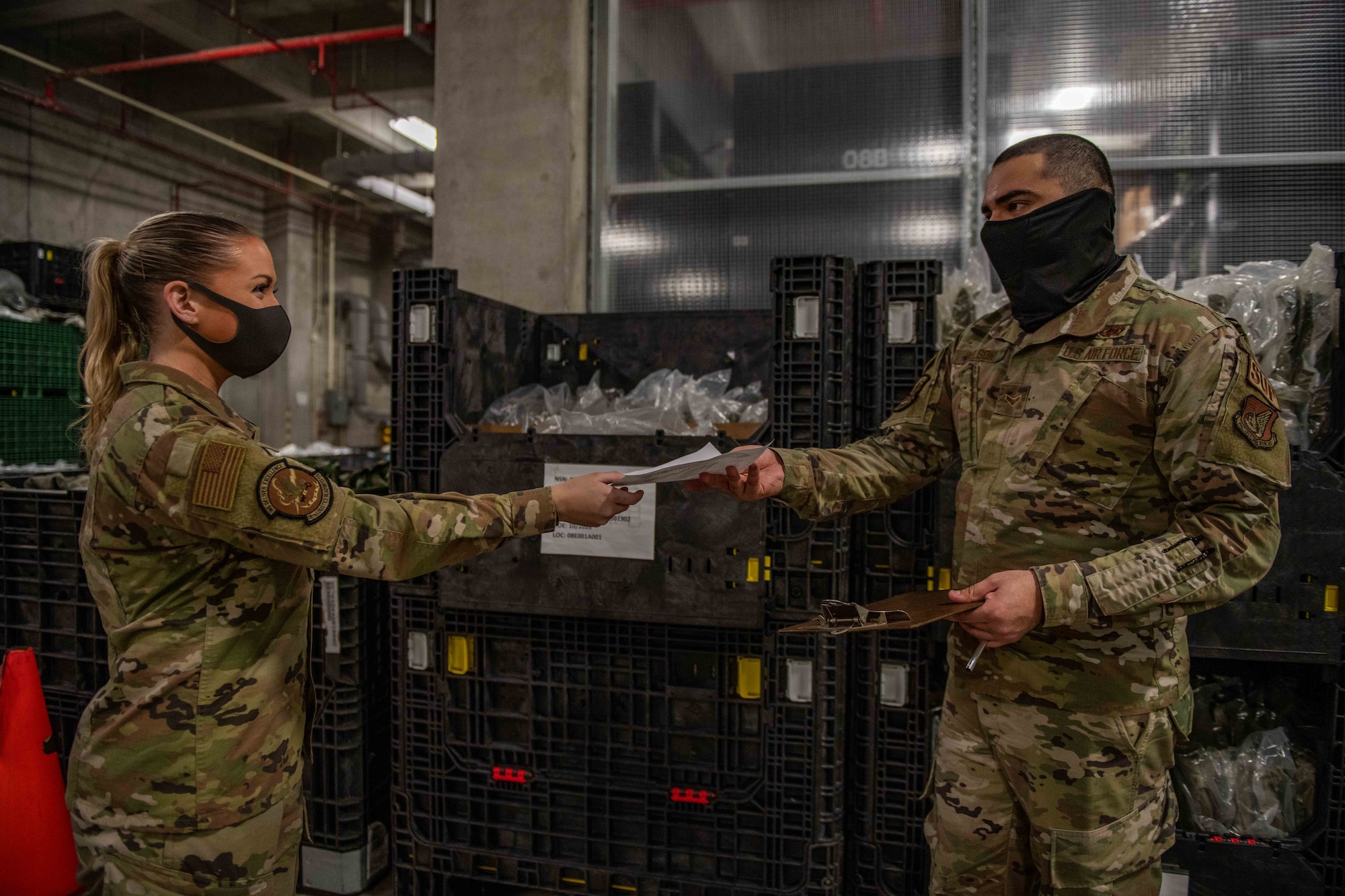 Airmen exchange forms near a bin of supplies